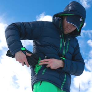 Male skier using the large rear storage pocket on his Arctica Down Packet instead of a backpack.