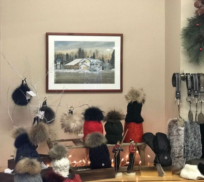 A painting of Rodgers Ski & Sport's original location on display with beautiful ski accessories for women.